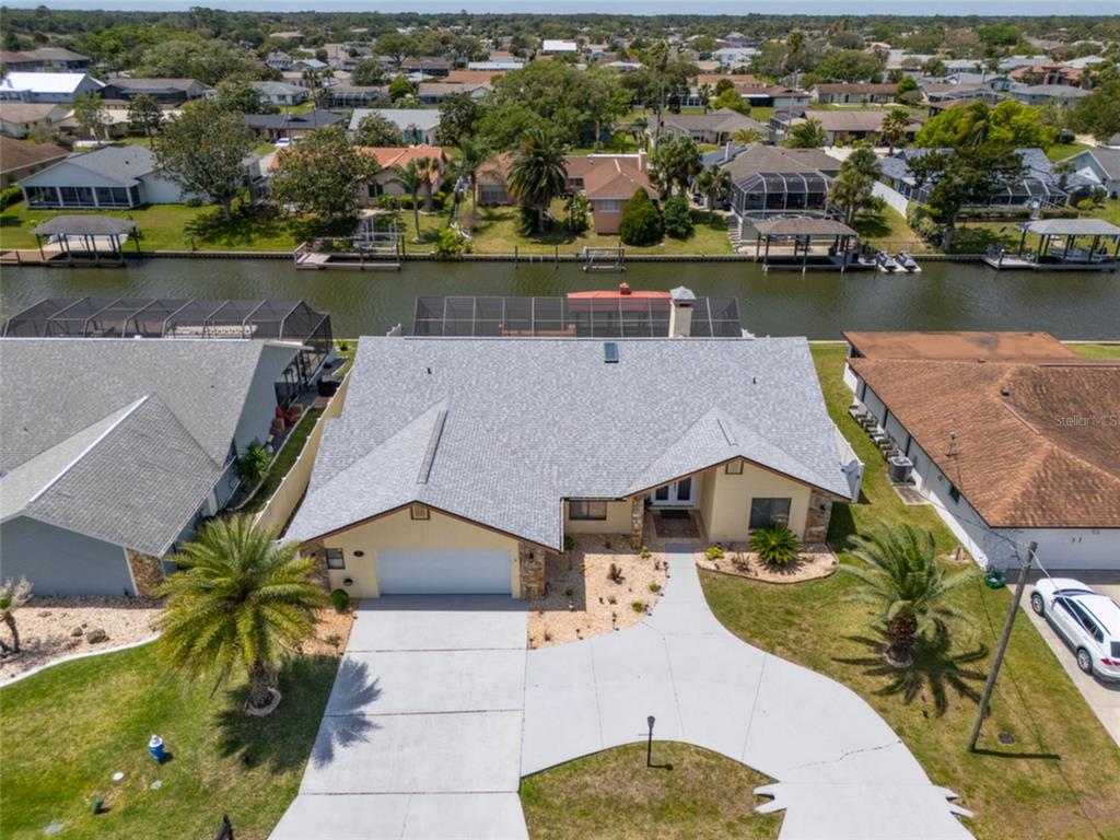A screened-in swimming pool with a patio overlooking a canal and neighboring houses — 18 CLASSIC COURT S, PALM COAST, FL