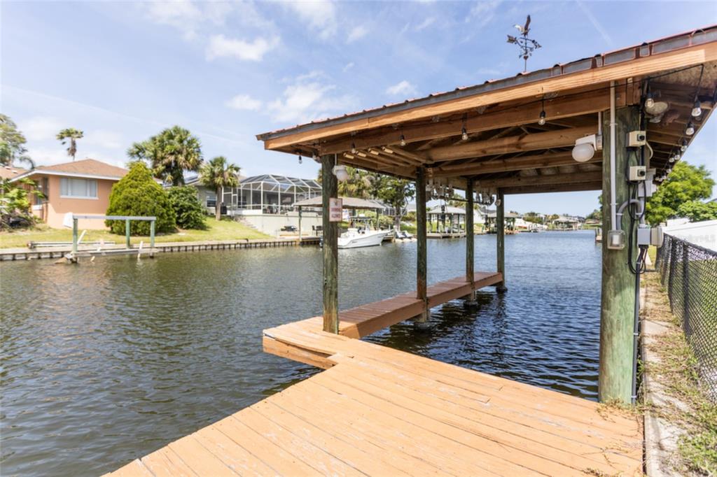 A screened-in pool deck features lounge chairs and patio seating overlooking a canal — 18 CLASSIC COURT S, PALM COAST, FL