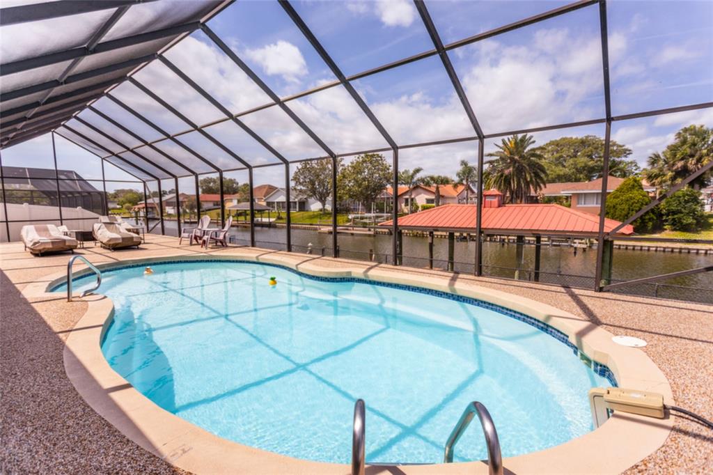 A wooden boat dock with a covered slip extends over a canal near residential homes — 18 CLASSIC COURT S, PALM COAST, FL