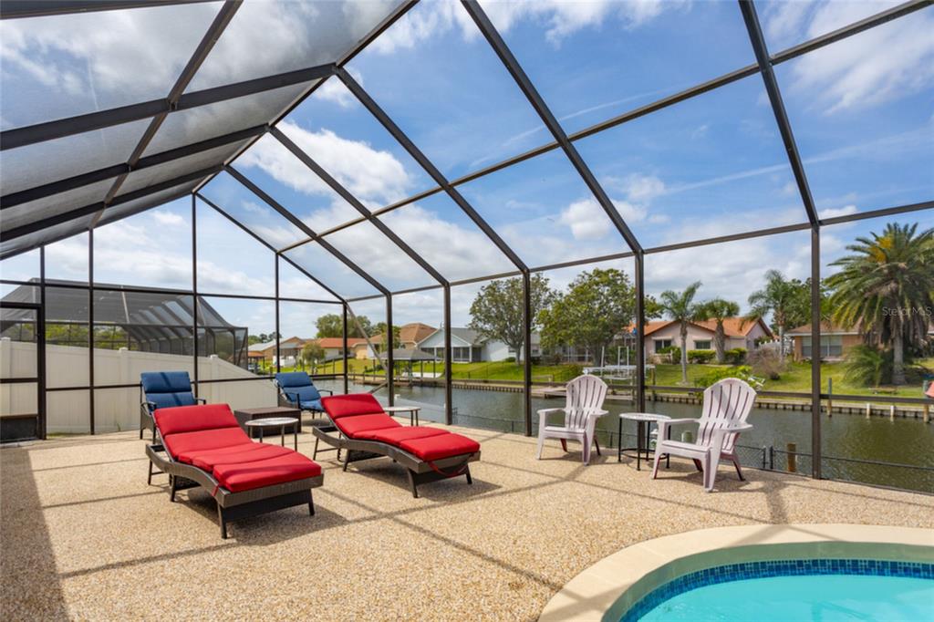 A wooden dock overlooks a canal lined with houses, boat lifts, and palm trees — 18 CLASSIC COURT S, PALM COAST, FL