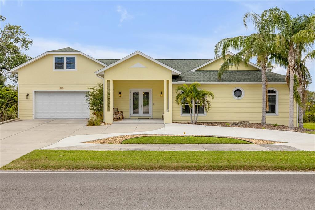 A yellow, single-story house with a two-car garage and a palm tree in the front yard — 1804 SAXON DRIVE, NEW SMYRNA BEACH, FL