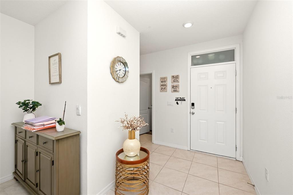 A tiled entryway features a wooden cabinet, a decorative side table, and a white door — 1791 POST OAK DRIVE, DAVENPORT, FL