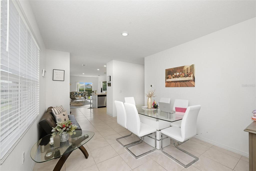 A dining area with a glass table and white chairs sits adjacent to a living space — 1791 POST OAK DRIVE, DAVENPORT, FL