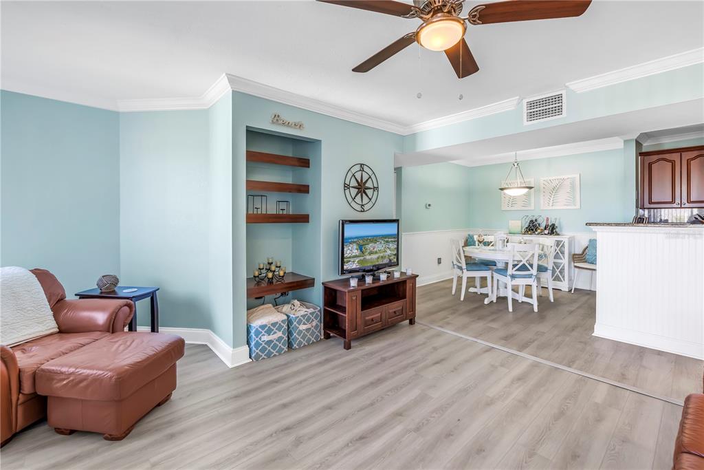This living and dining area features light blue walls, wood-look flooring, and a built-in shelf — 455 ALT 19 S UNIT 266, PALM HARBOR, FL