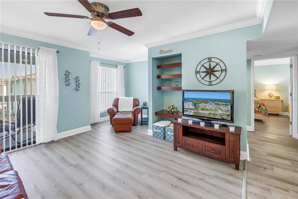 A living room features light blue walls, wood-look flooring, a ceiling fan, and a television console — 455 ALT 19 S UNIT 266, PALM HARBOR, FL