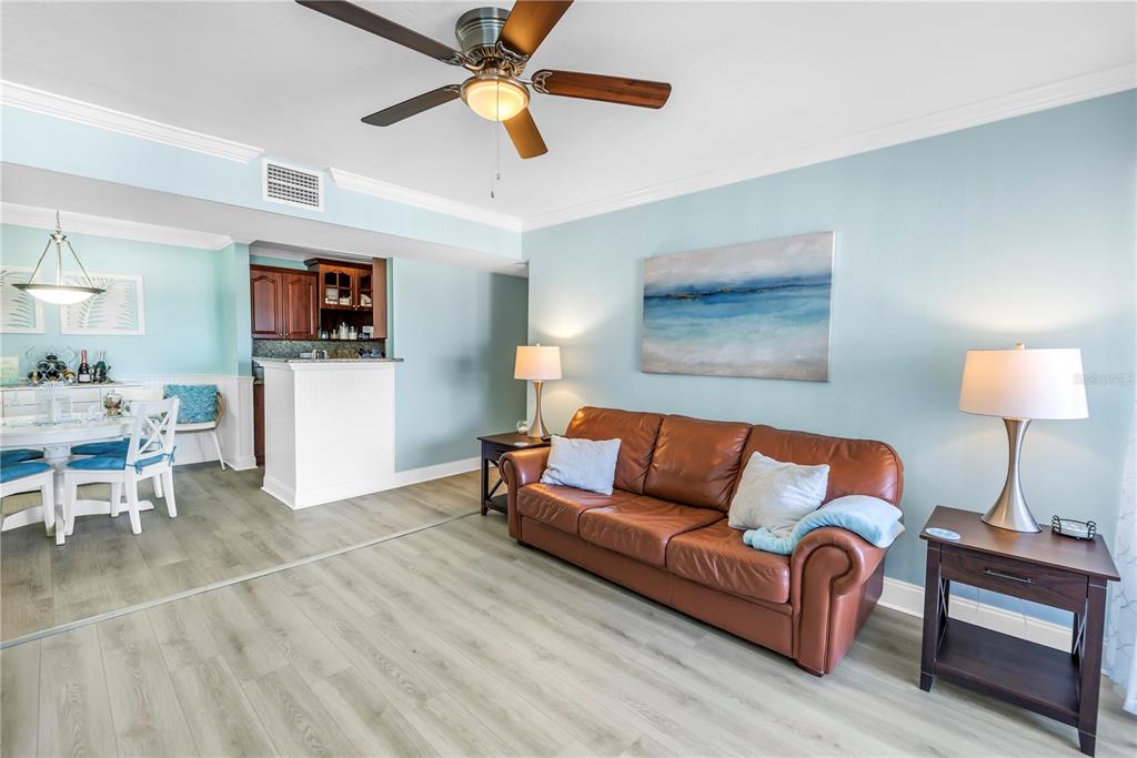 A living room with light blue walls, a brown leather sofa, and wood-look flooring — 455 ALT 19 S UNIT 266, PALM HARBOR, FL
