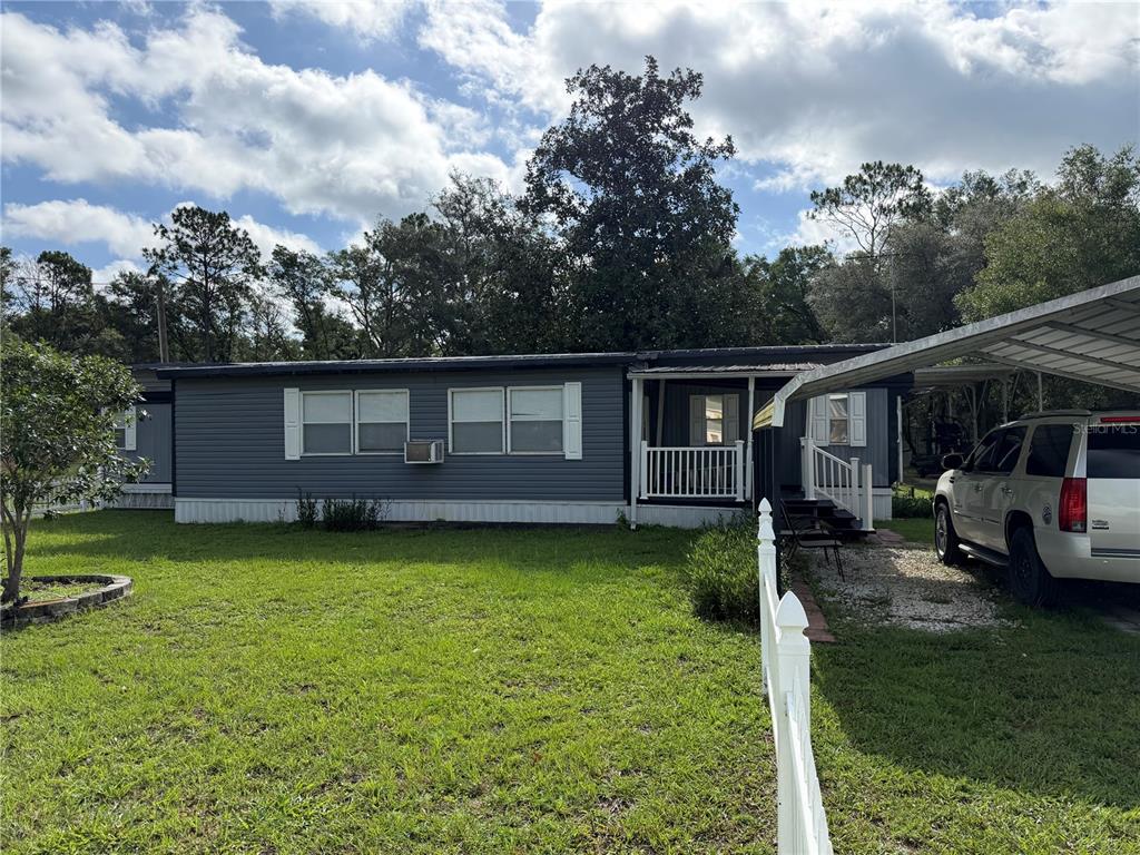 A single-story manufactured home with grey siding, a front porch, and an attached carport — 111 SW 158TH TERRACE, OCALA, FL
