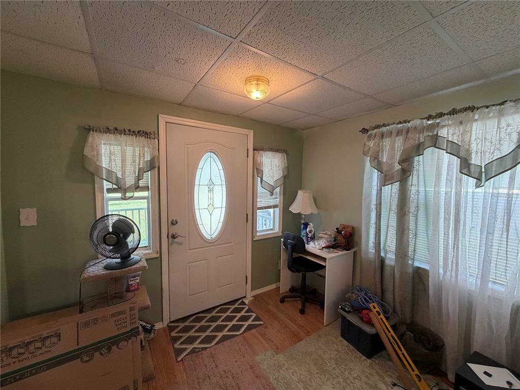 An entryway with a white front door, light green walls, and a drop ceiling — 111 SW 158TH TERRACE, OCALA, FL