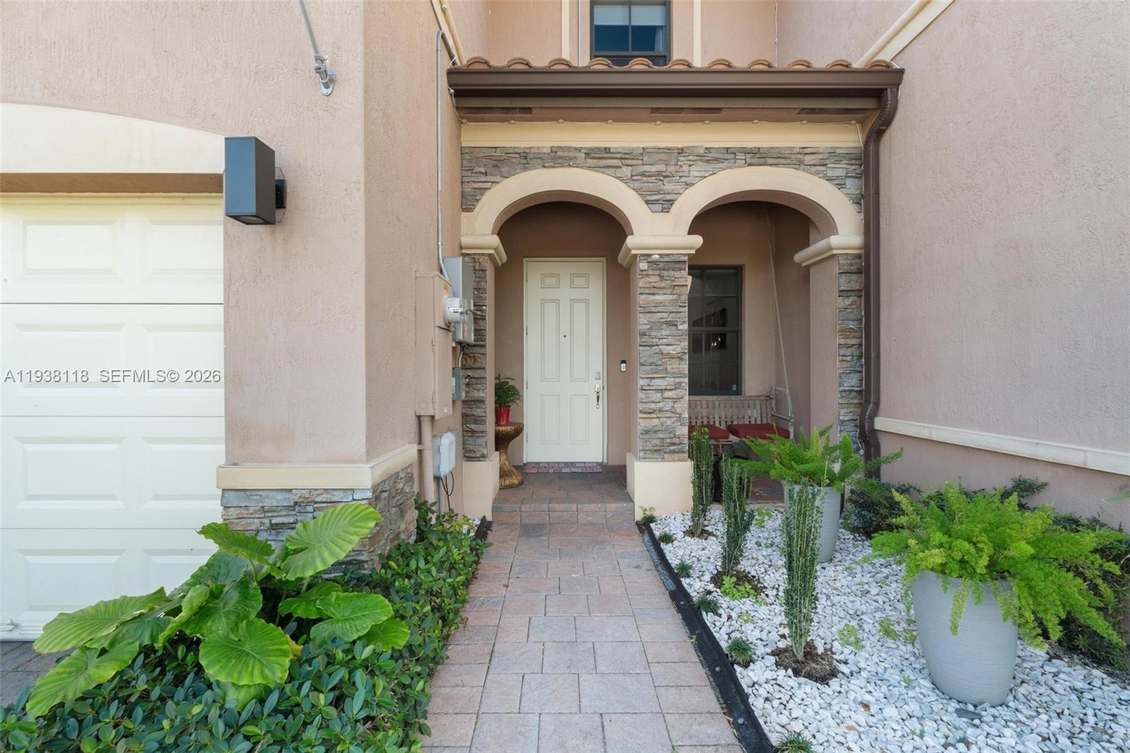 A paved walkway leads to a front door framed by stone arches and a porch — 3436 W 90th St, Hialeah FL 33018, HIALEAH, FL