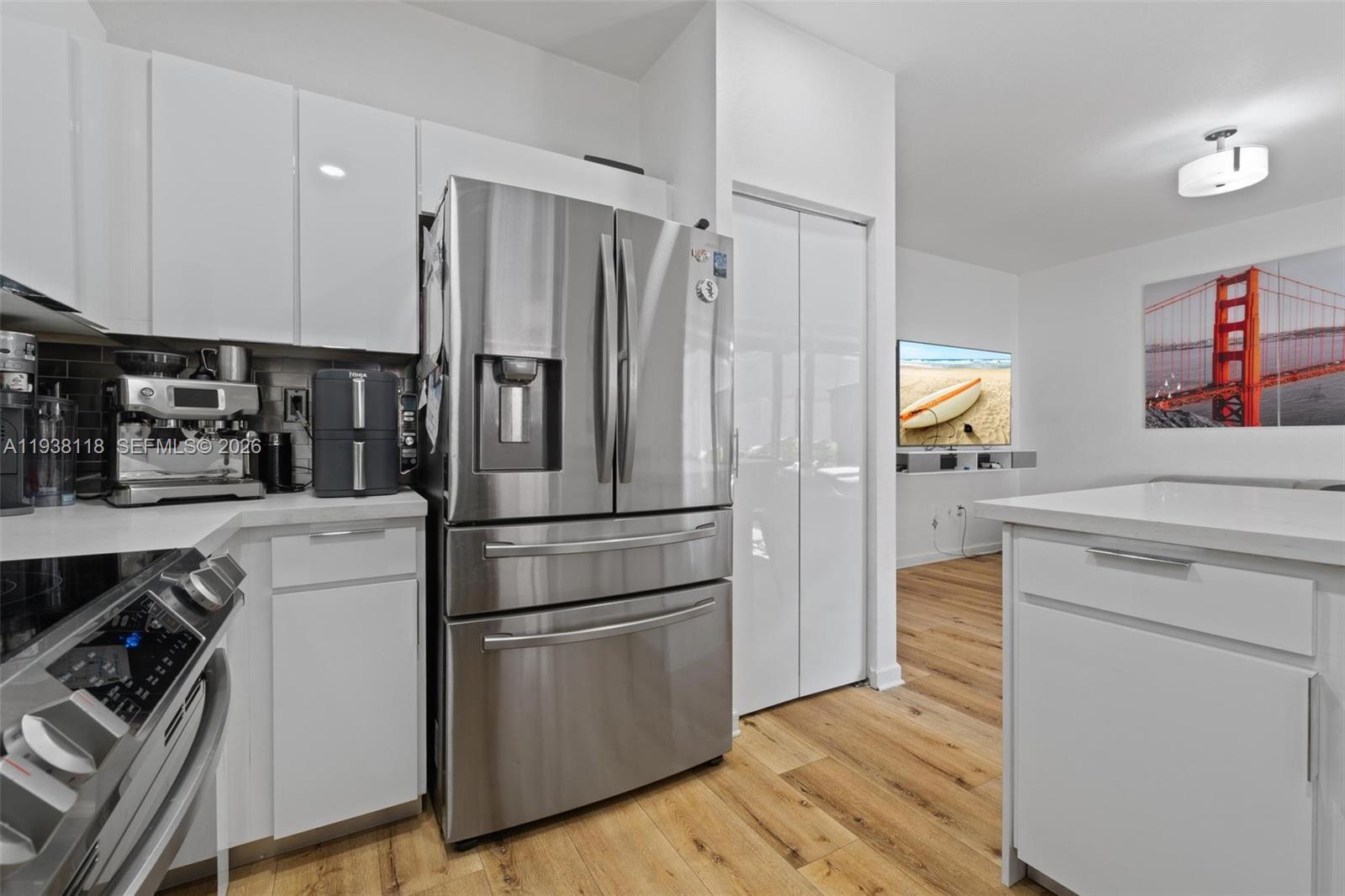 A modern kitchen features white cabinets, stainless steel appliances, and wood-look flooring — 3436 W 90th St, Hialeah FL 33018, HIALEAH, FL