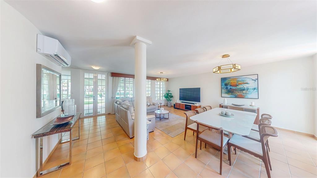 An open-concept living and dining area features tile flooring, a central pillar, and glass doors — 53 CALLE ARRECIFE, DORADO, PR