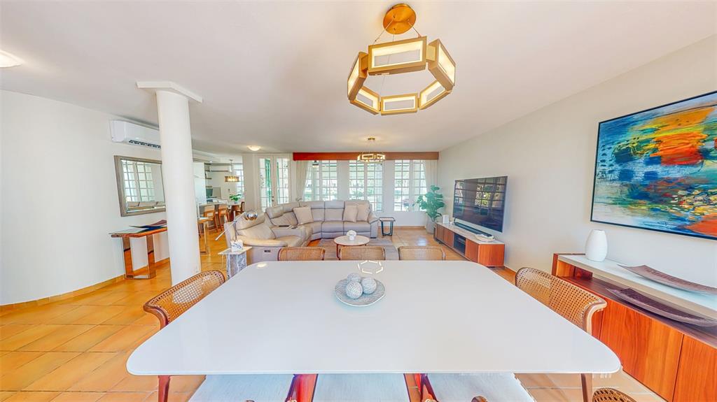 A dining area with a white table and cane chairs opens into a living room — 53 CALLE ARRECIFE, DORADO, PR