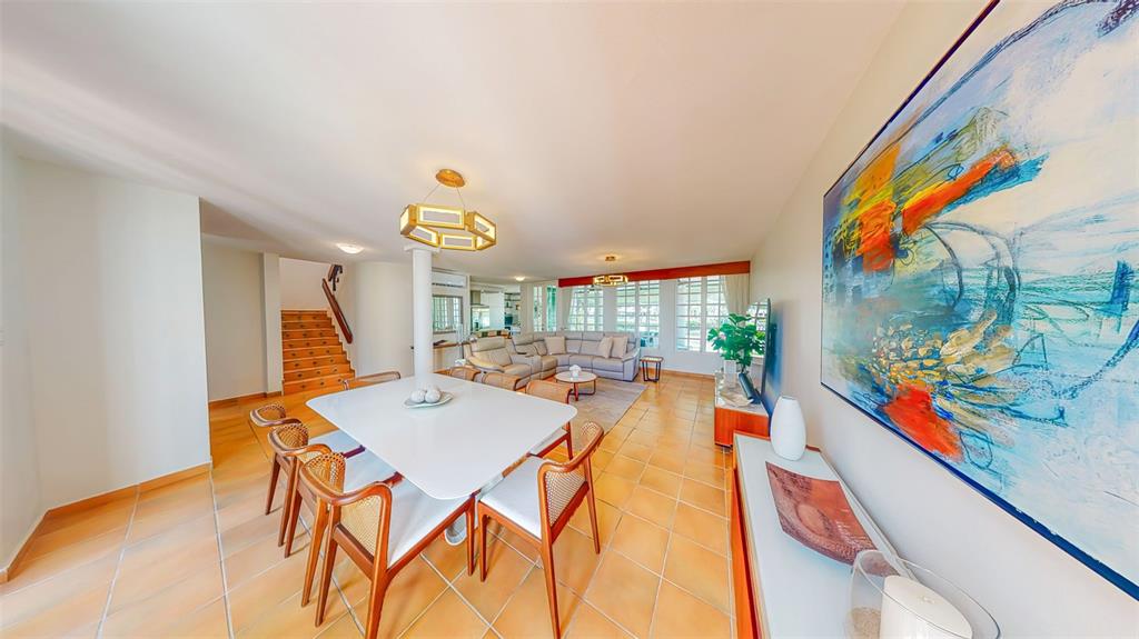 A dining area with a white table and wooden chairs opens into a living room — 53 CALLE ARRECIFE, DORADO, PR