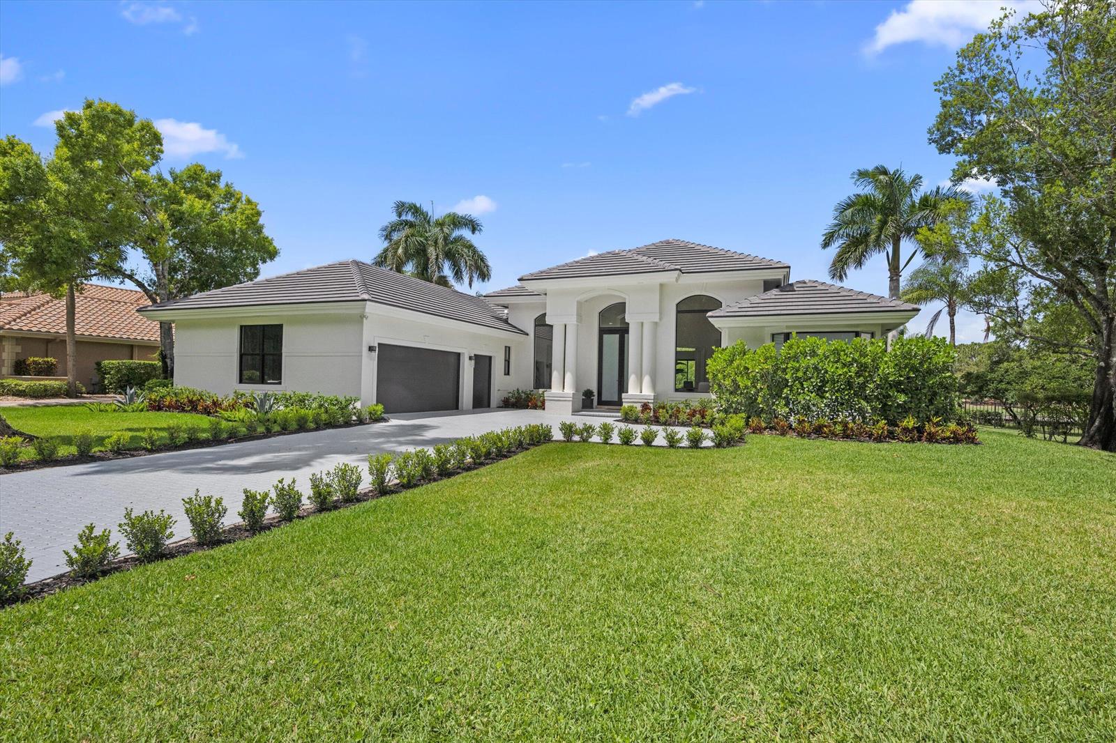 A single-story white house with a gray tile roof and a paved driveway — 1330 Breakers West Boulevard, West Palm Beach FL 33411, WEST PALM BEACH, FL