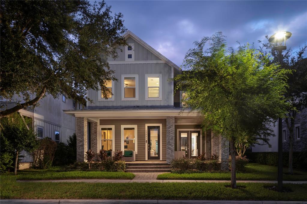 A two-story house with a front porch, gray siding, and stone pillars at dusk — 13041 GABOR AVENUE, ORLANDO, FL