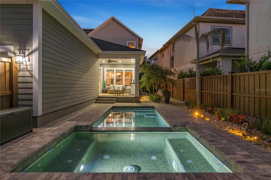 A backyard features a rectangular pool and spa surrounded by brick pavers at dusk — 13041 GABOR AVENUE, ORLANDO, FL