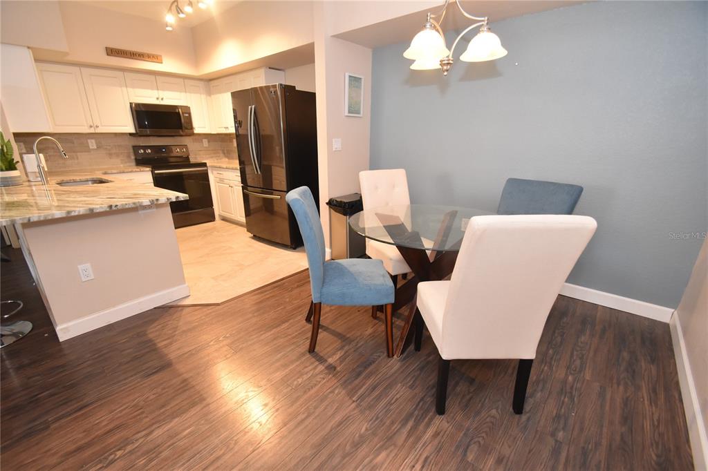 A kitchen with white cabinets and a dining area featuring a glass table and chairs — 4178 CENTRAL SARASOTA PARKWAY UNIT 324, SARASOTA, FL