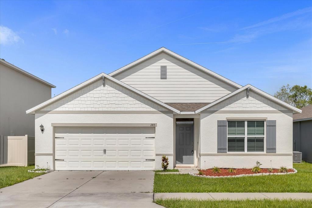 A single-story house with a white stucco facade, gray shutters, and a two-car garage — 285 SUMMERSHORE DRIVE, AUBURNDALE, FL