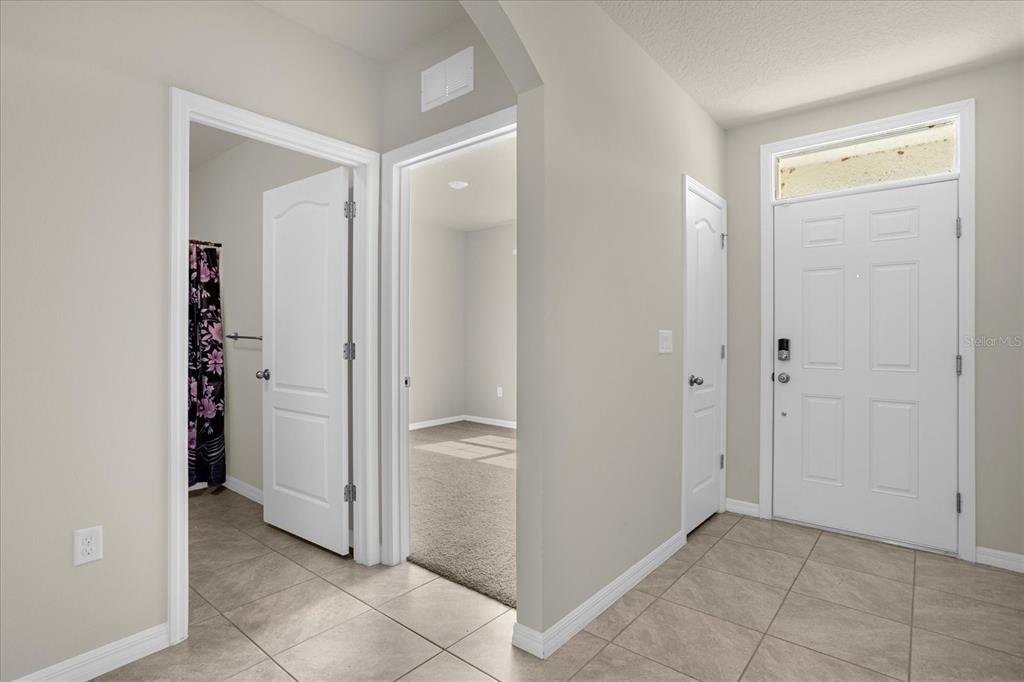 An entryway with tile flooring, a white front door, and two interior doorways — 285 SUMMERSHORE DRIVE, AUBURNDALE, FL