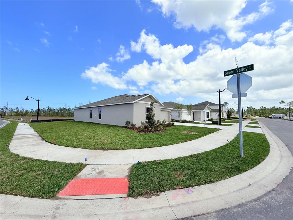 A corner lot features a newly constructed single-story house with a sidewalk and street sign — 1310 BELLE ISLE LANE, DAYTONA BEACH, FL