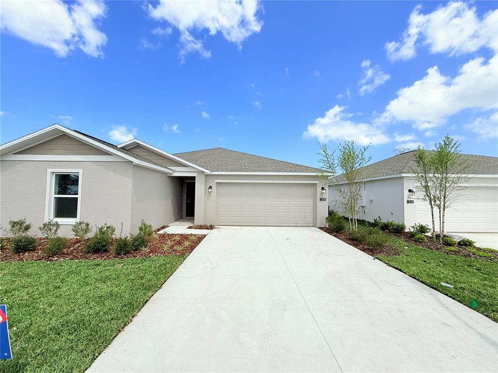 A single-story house with a beige exterior, a two-car garage, and a concrete driveway — 1310 BELLE ISLE LANE, DAYTONA BEACH, FL