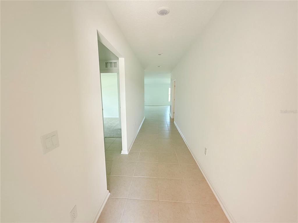 A long, tiled hallway leads toward an open living area with light-colored walls — 1310 BELLE ISLE LANE, DAYTONA BEACH, FL