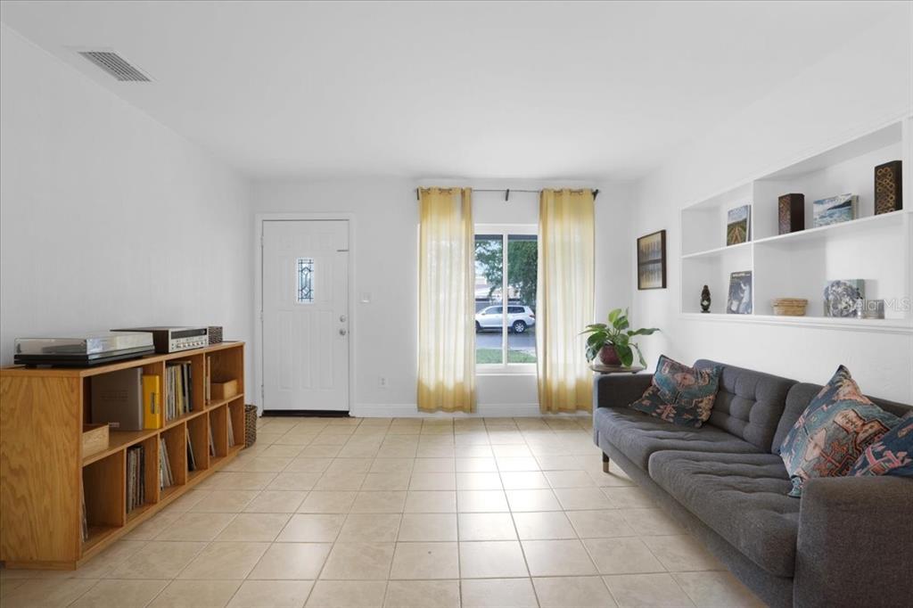 A living room features light tile floors, a grey sofa, built-in shelving, and a front door — 1032 NE 19TH PLACE, GAINESVILLE, FL