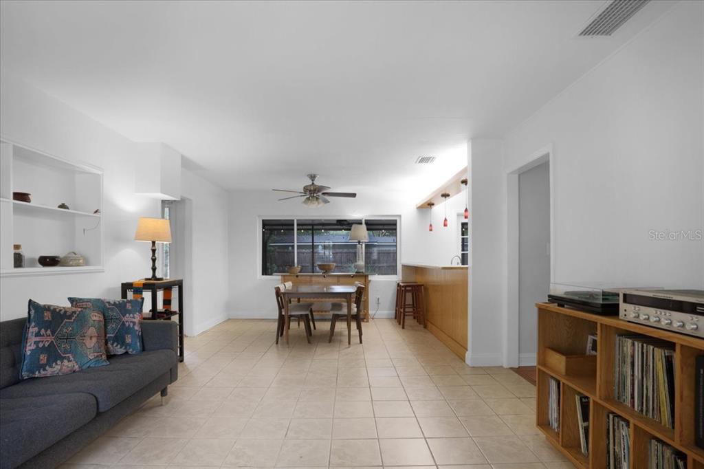 A living and dining area with tile floors, a ceiling fan, and a breakfast bar — 1032 NE 19TH PLACE, GAINESVILLE, FL