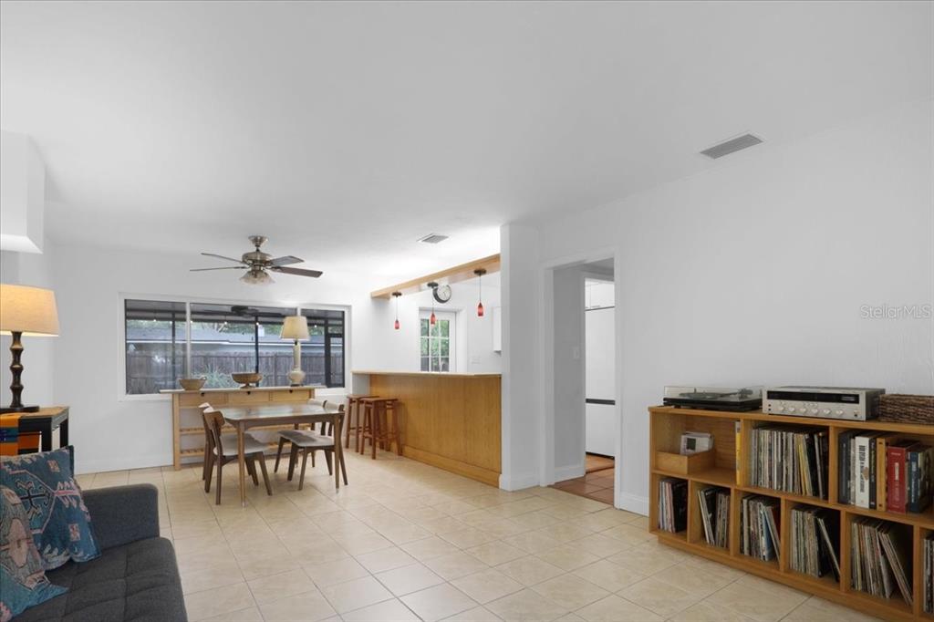 A living and dining area with tile floors, a wooden breakfast bar, and built-in shelving — 1032 NE 19TH PLACE, GAINESVILLE, FL