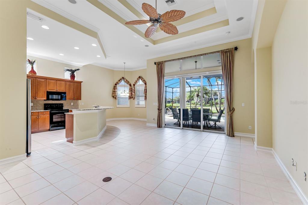 An open-concept kitchen and living area with tile floors, a ceiling fan, and sliding doors — 12584 GRANDEZZA CIRCLE, ESTERO, FL