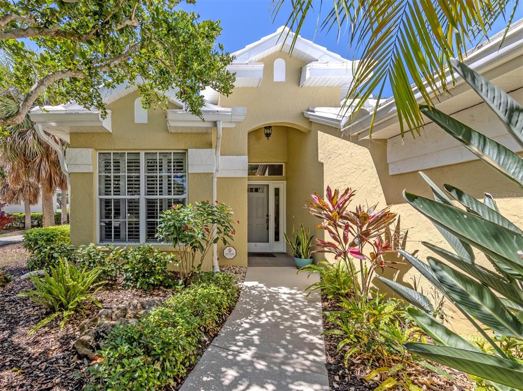 A tan stucco house exterior with a white-trimmed front door and a concrete walkway — 535 FALLBROOK DRIVE, VENICE, FL