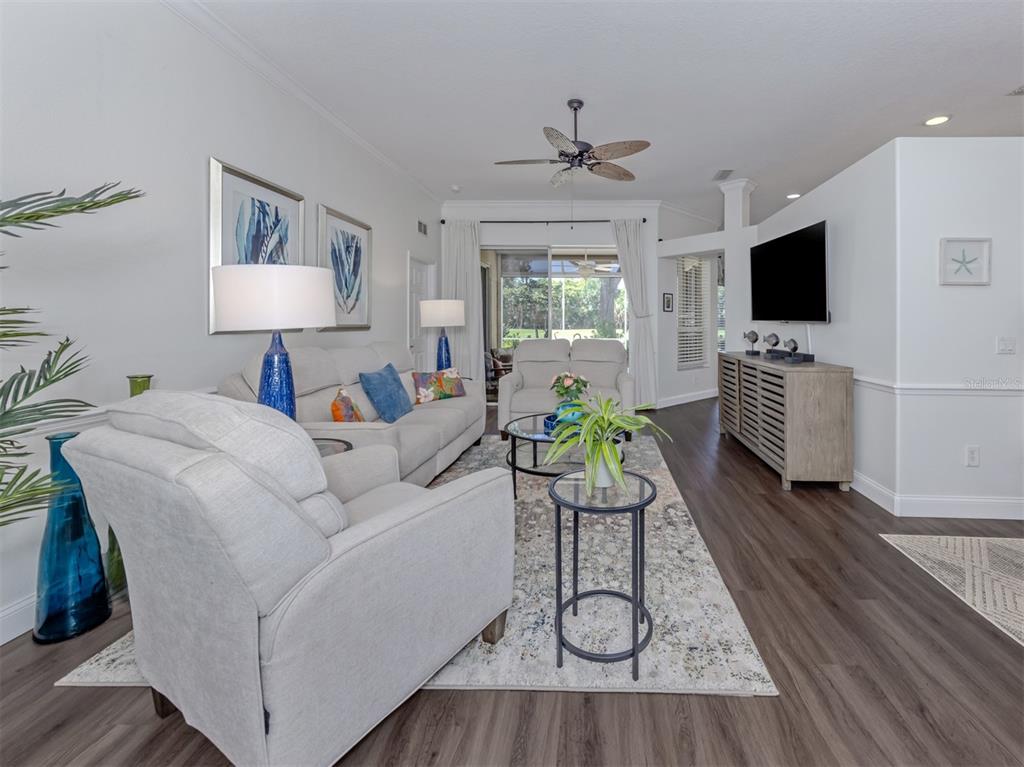 A living room features light-colored furniture, a patterned area rug, and dark wood-look flooring — 535 FALLBROOK DRIVE, VENICE, FL