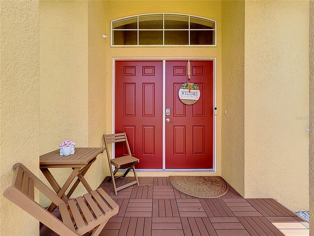 A front porch features red double doors, a small wooden table, and two folding chairs — 8230 WOODVINE CIRCLE, LAKELAND, FL