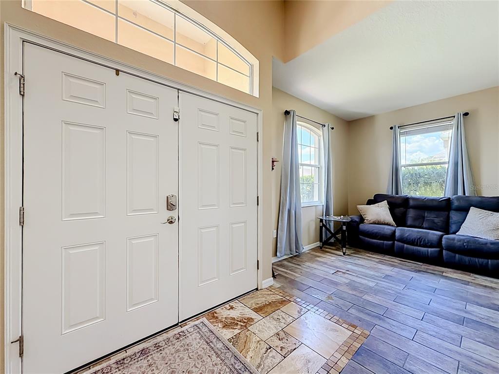 A foyer with tile flooring leads into a living area featuring wood-look tile and a sofa — 8230 WOODVINE CIRCLE, LAKELAND, FL