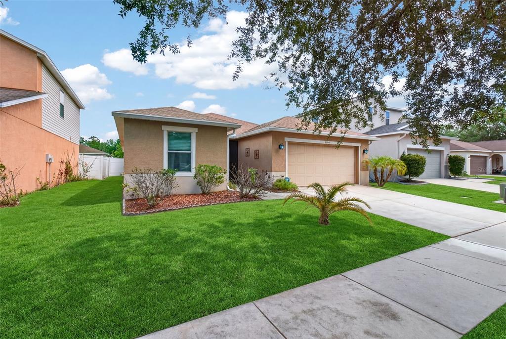 A single-story suburban house with a tan stucco exterior, two-car garage, and green lawn — 11154 RUNNING PINE DRIVE DRIVE, RIVERVIEW, FL