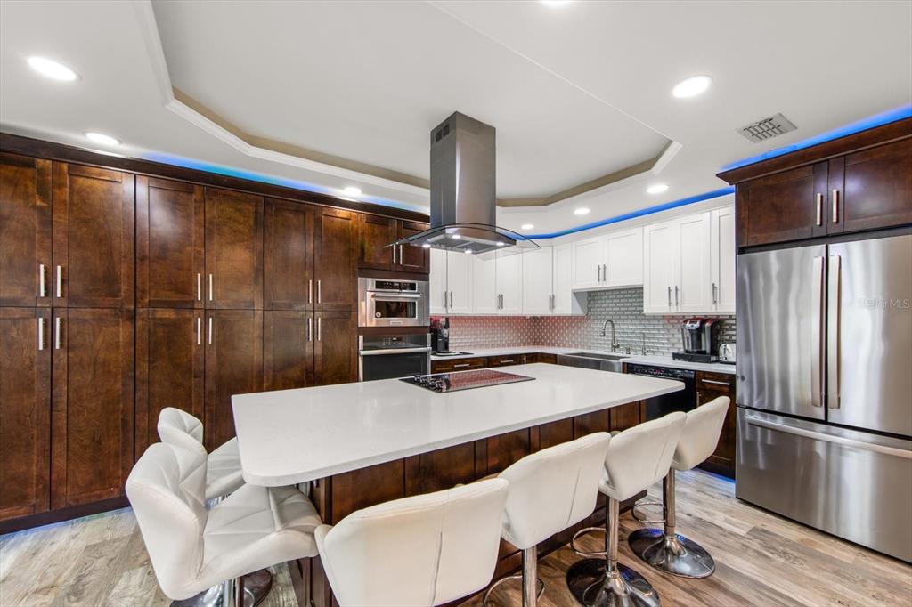 A modern kitchen features dark wood cabinetry, white upper cabinets, a large island, and stainless appliances — 5015 20TH AVENUE N, ST PETERSBURG, FL