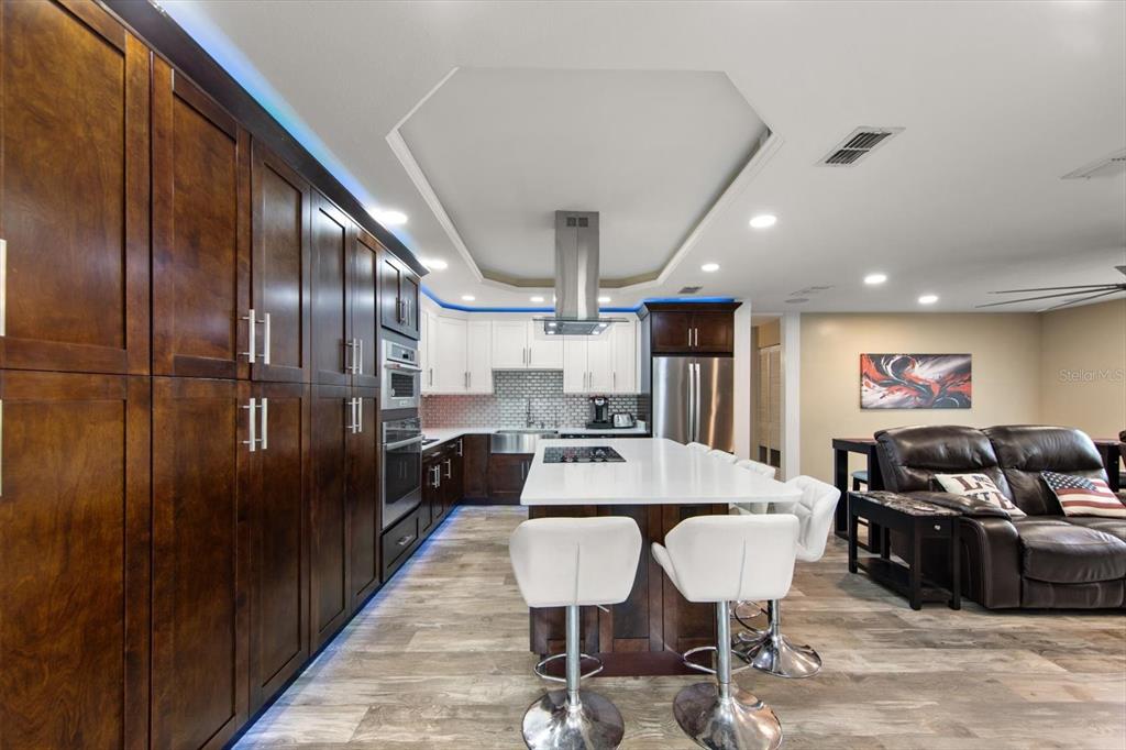 A modern kitchen features dark wood cabinetry, a white island with bar seating, and recessed lighting — 5015 20TH AVENUE N, ST PETERSBURG, FL