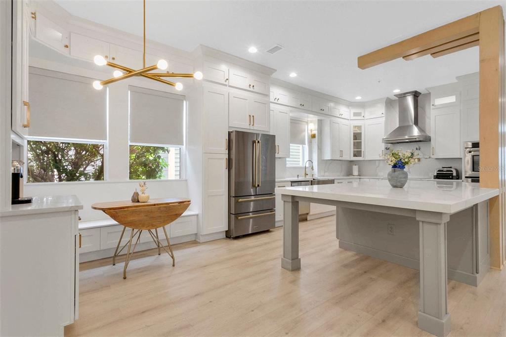 A modern kitchen features white cabinetry, a large central island, and a breakfast nook area — 3069 STANFIELD AVENUE, ORLANDO, FL