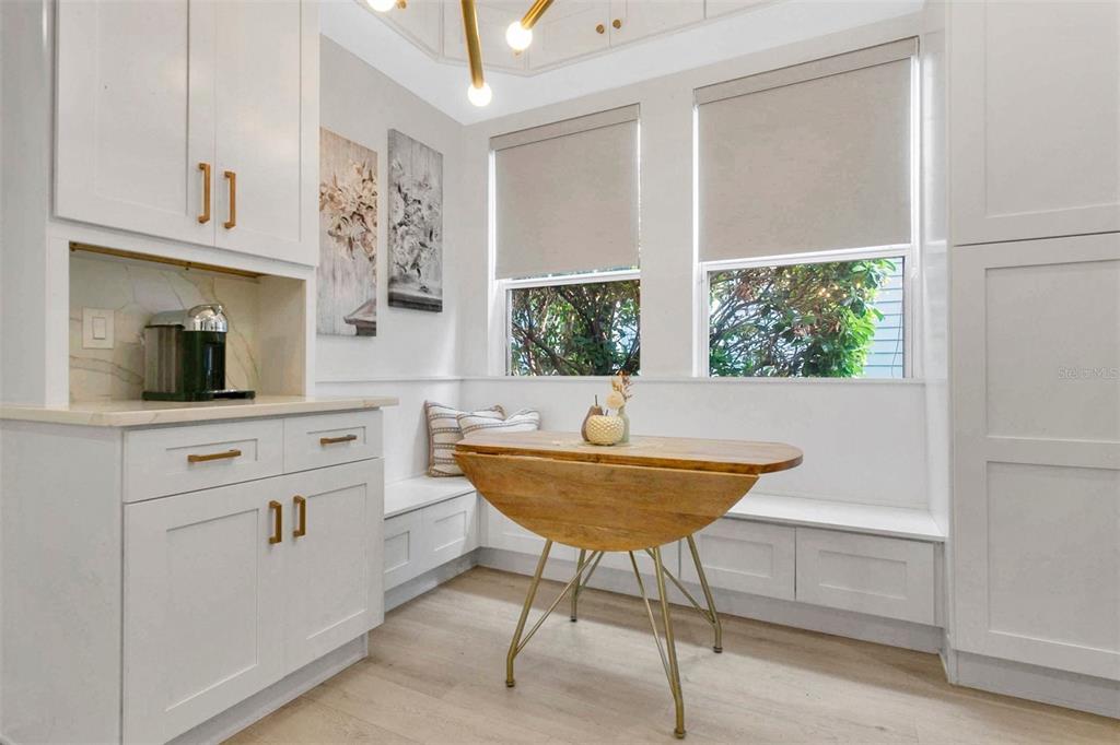 A breakfast nook features white cabinetry, a wooden drop-leaf table, and built-in bench seating — 3069 STANFIELD AVENUE, ORLANDO, FL