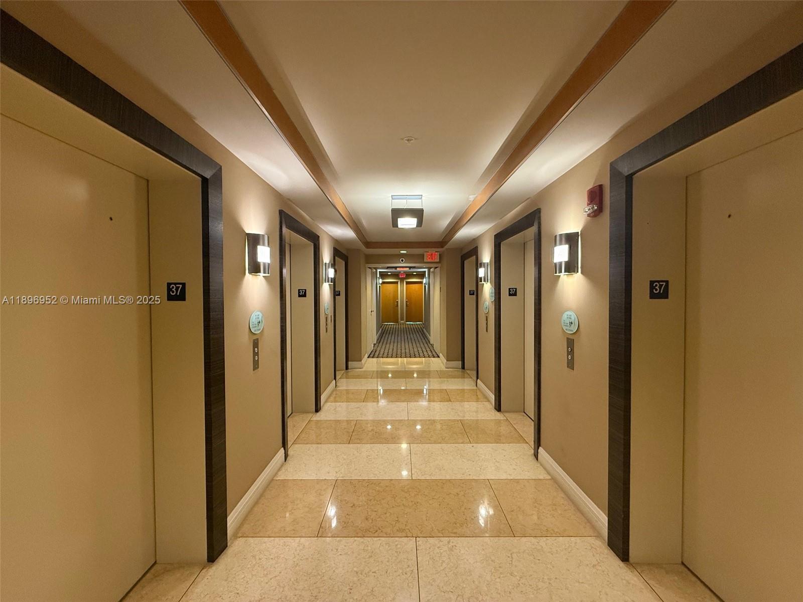A brightly lit apartment building hallway features beige tiled floors and multiple unit doors — 244 Biscayne Blvd # 3708, Miami FL 33132, MIAMI, FL