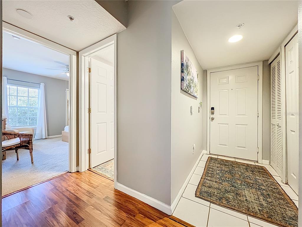 An entryway with white tile floors, a front door, and a doorway to a bedroom — 12602 CREST SPRINGS LANE UNIT 1333, ORLANDO, FL