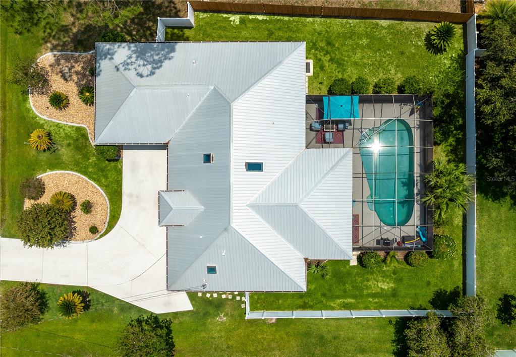 An aerial view shows a house with a metal roof, a screened pool, and landscaping — 54 FORDHAM LANE, PALM COAST, FL