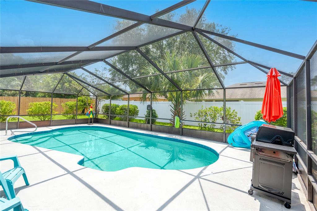 A screened-in swimming pool with a patio, grill, and a white vinyl privacy fence — 54 FORDHAM LANE, PALM COAST, FL
