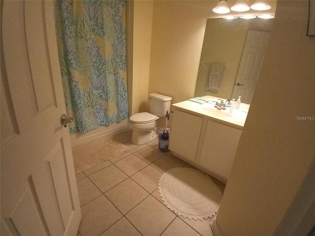 A bathroom features a tiled floor, a white vanity, a toilet, and a coral-patterned shower curtain — 1121 SETON HALL COURT, SANFORD, FL