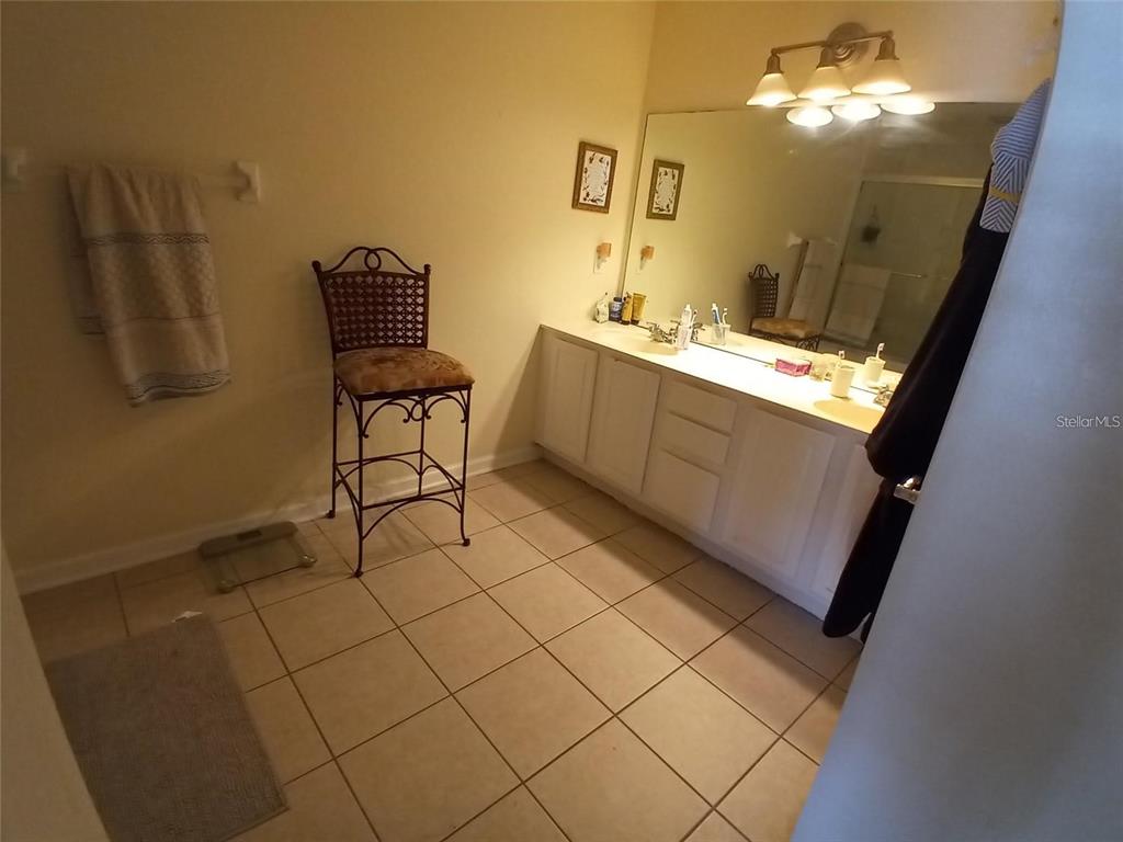 A bathroom features a white double vanity, a large mirror, and a tall metal chair — 1121 SETON HALL COURT, SANFORD, FL