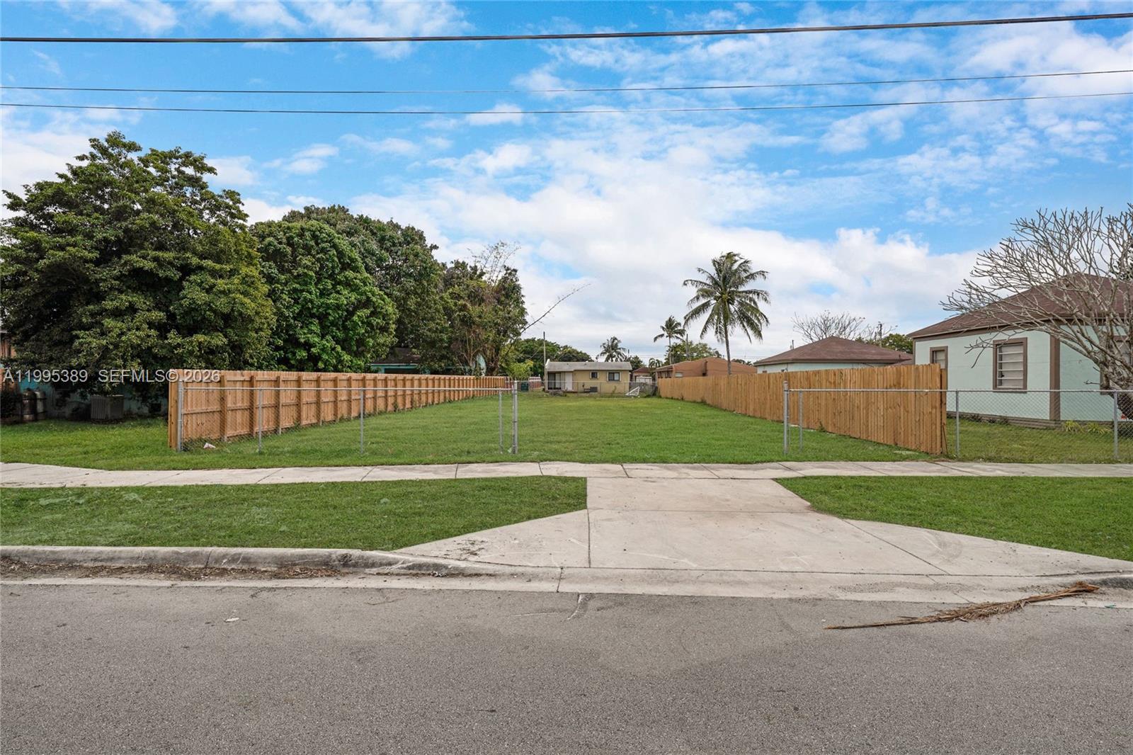 A vacant rectangular residential lot is enclosed by wooden fences with a concrete driveway entrance — nw 2, Florida City FL 33034, FLORIDA CITY, FL