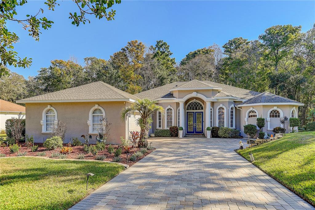 A single-story house with a paved driveway, arched windows, and a blue double front door — 12054 QUAIL RIDGE DRIVE, SPRING HILL, FL