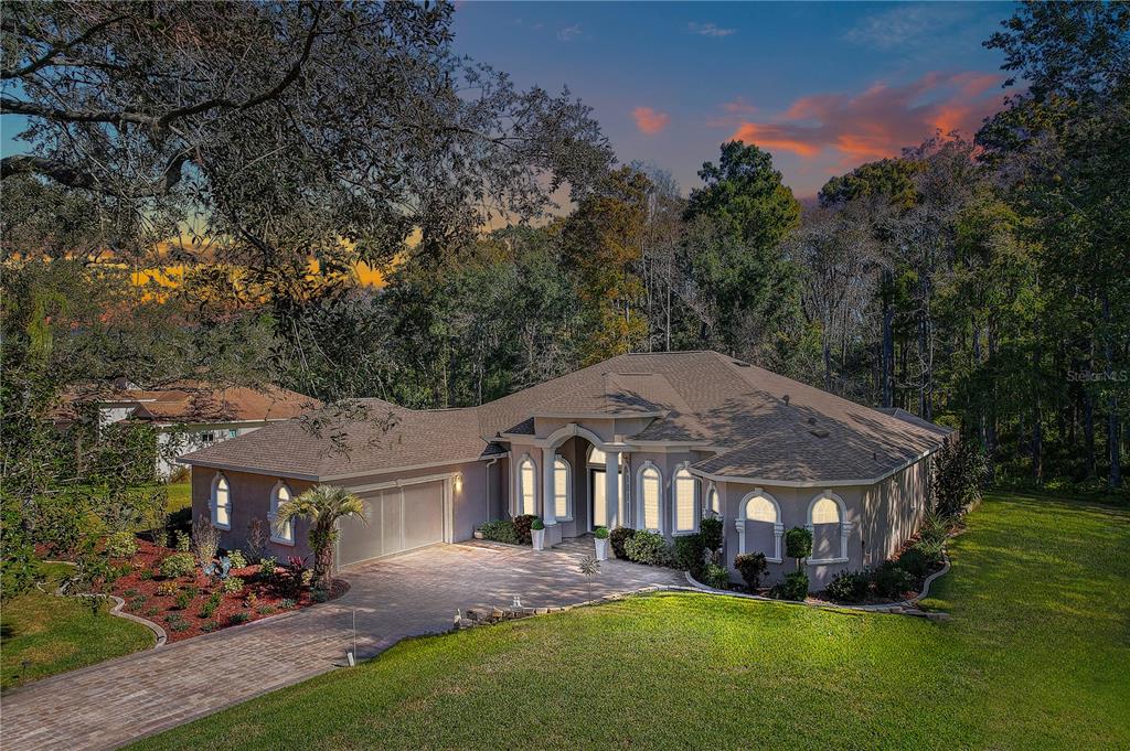 A single-story house with a paved driveway, arched windows, and a multi-car garage — 12054 QUAIL RIDGE DRIVE, SPRING HILL, FL