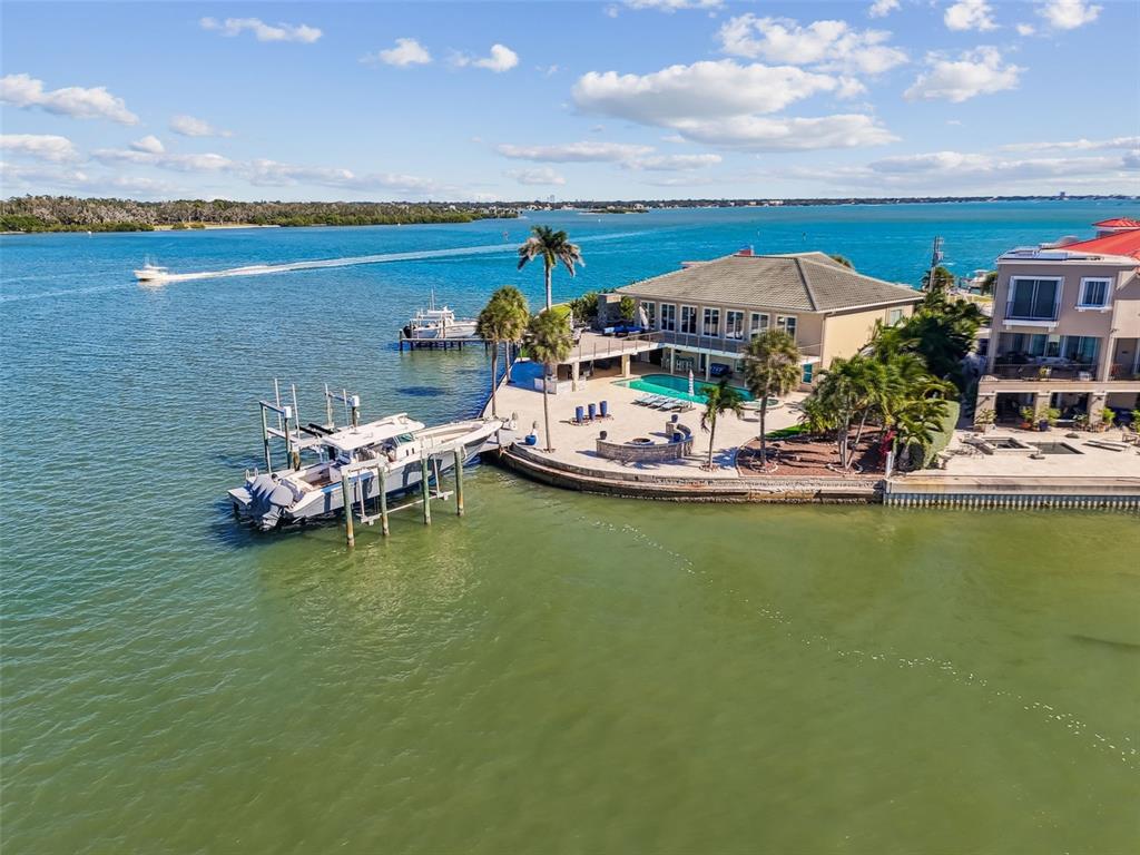 An aerial view shows a waterfront house with a pool, dock, and two boats — 582 JOHNS PASS AVENUE, MADEIRA BEACH, FL