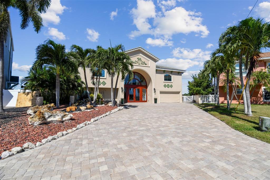 A two-story house with a paved driveway, palm trees, and a large arched entryway — 582 JOHNS PASS AVENUE, MADEIRA BEACH, FL